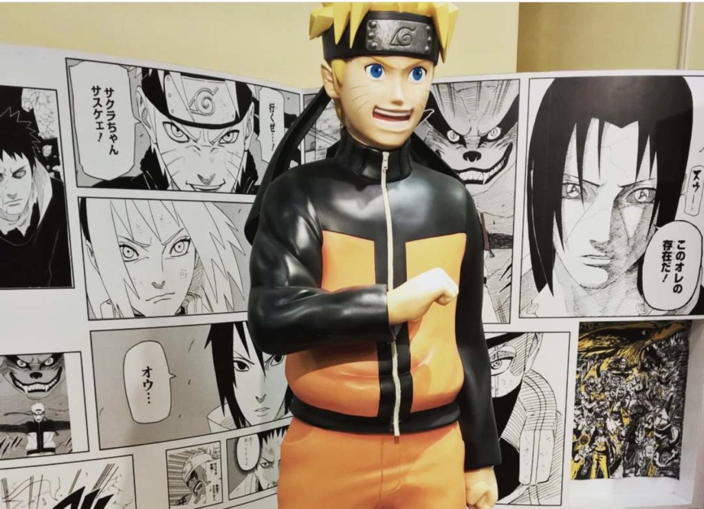 Naruto levensgrote figuur met manga achter hem